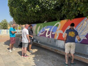 Grupo de personas trabajando en un mural de orgullo LGTBIQ+ en Foios