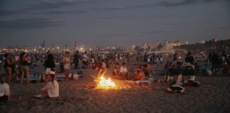 Celebración de la Nit de Sant Joan en la playa de Valencia con fogatas y gente disfrutando.