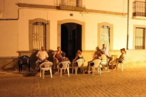Grupo de personas sentadas en sillas en la calle durante la noche