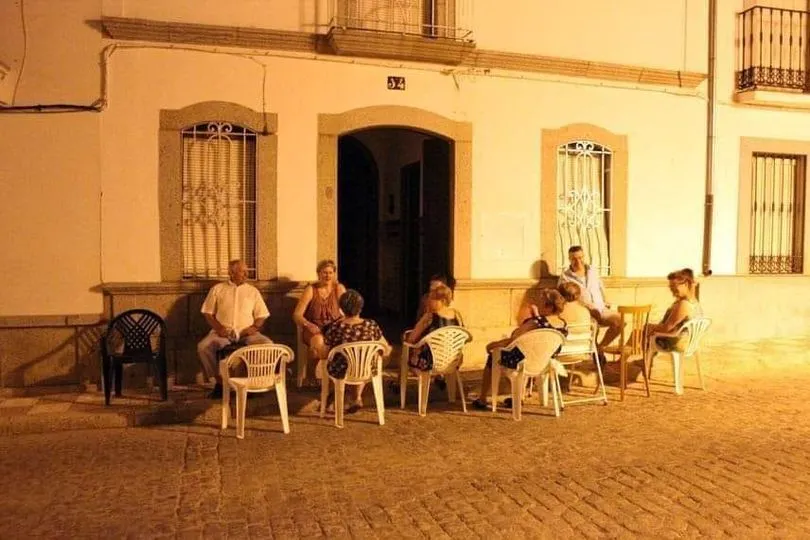 Grupo de personas sentadas en sillas en la calle durante la noche