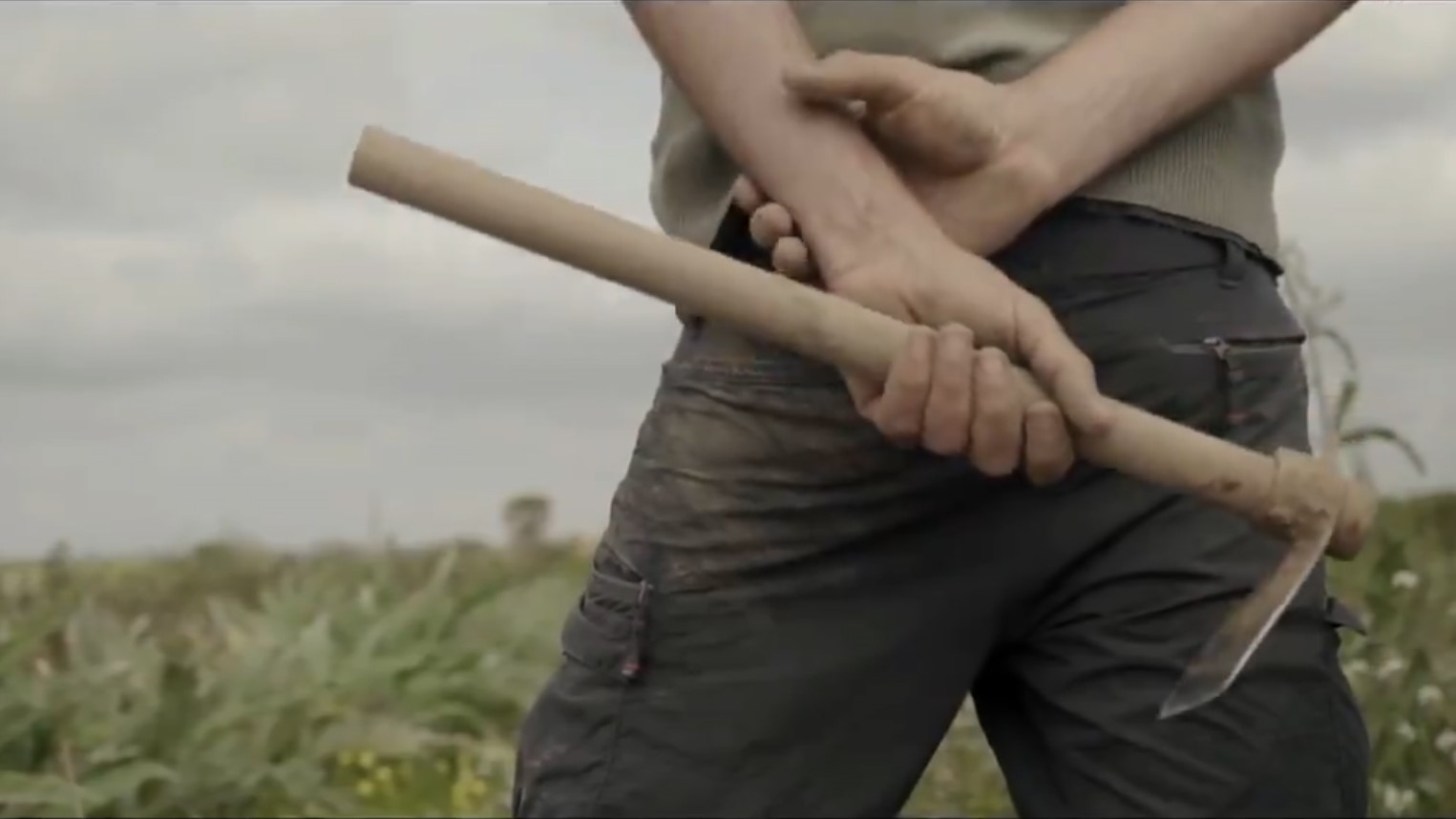 Persona sosteniendo una herramienta agrícola en un campo