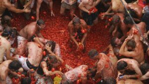 Participantes disfrutando de la Tomatina en Buñol, rodeados de tomates.