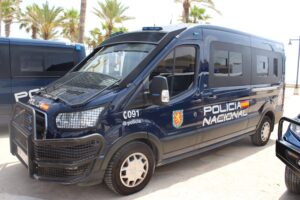 Furgón de la Policía Nacional en Valencia, estacionado junto a palmeras.