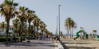 Paseo en la playa de Les Arenes con palmeras y visitantes