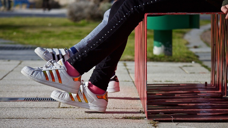 Pies de niños con zapatillas en un banco en Orriols, Valencia