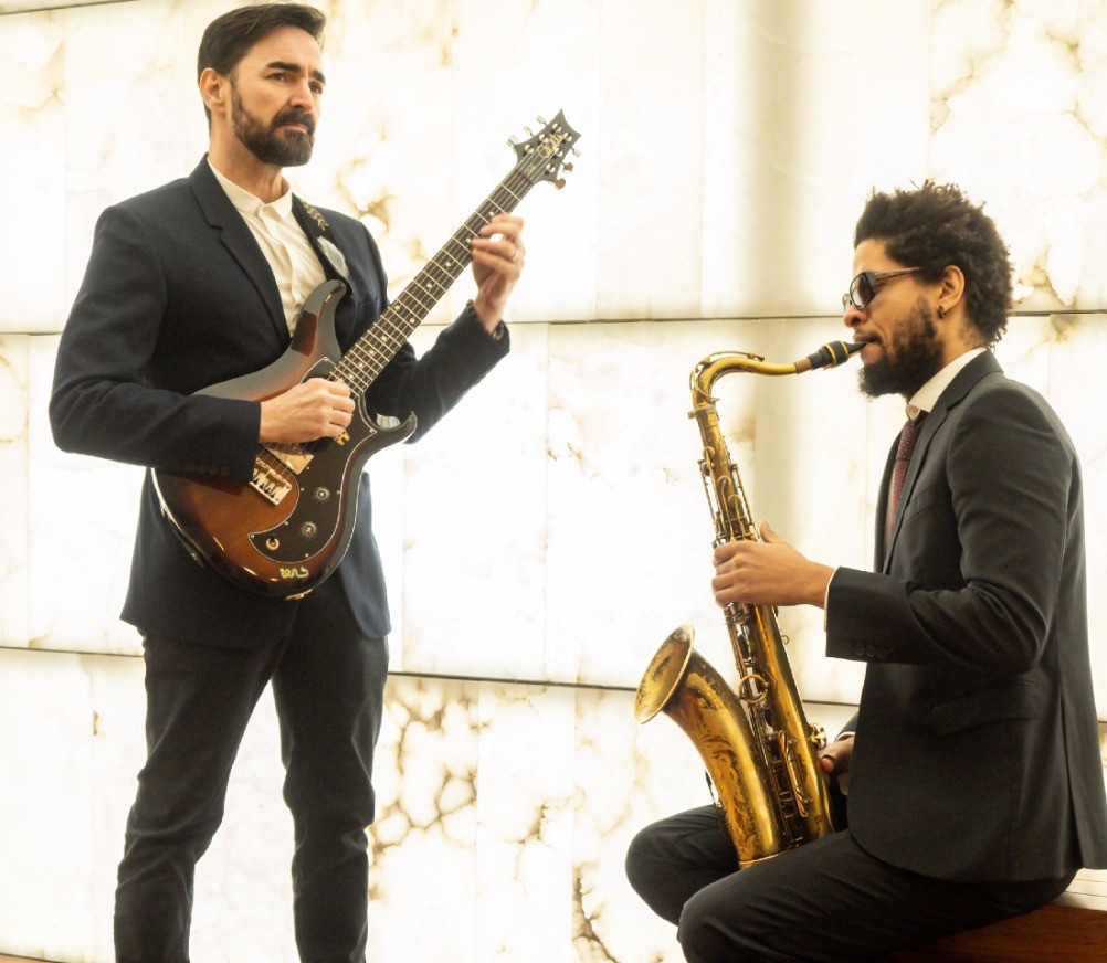 Ariel Brínguez con saxofón y Javier Sánchez con guitarra en un escenario Ariel Brínguez con saxofón y Javier Sánchez con guitarra en un escenario