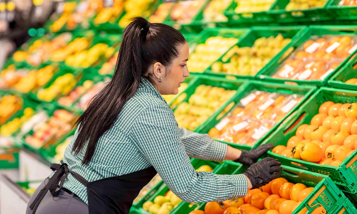 Trabajadora organizando caqui en un supermercado Mercadona