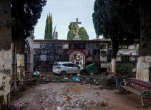 Vista de un cementerio con daños por inundación y un coche atrapado.