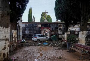 Vista de un cementerio con daños por inundación y un coche atrapado.