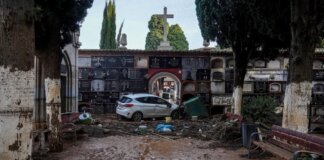 Vista de un cementerio con daños por inundación y un coche atrapado.