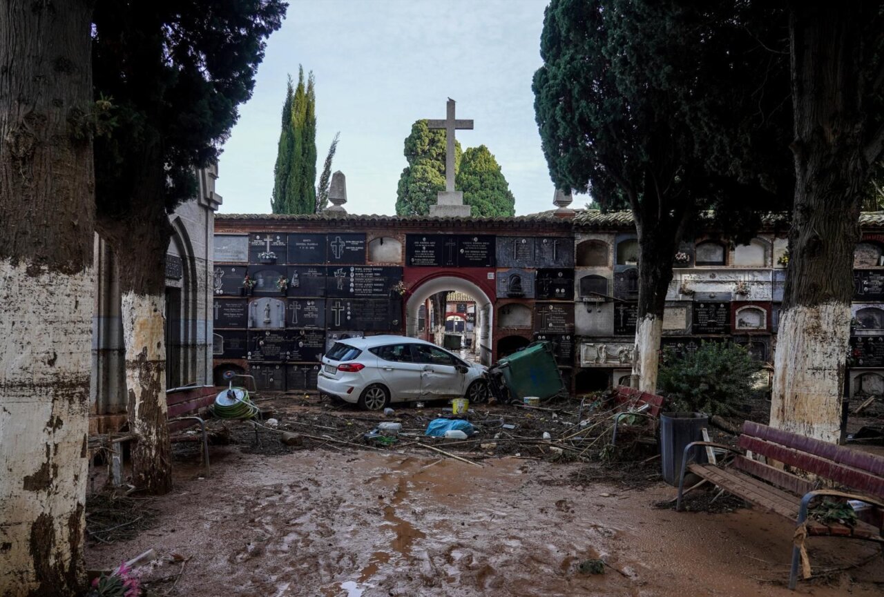 Vista de un cementerio con daños por inundación y un coche atrapado.