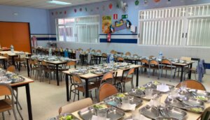 Comedor escolar con mesas y platos preparados para los estudiantes.