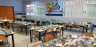 Comedor escolar con mesas y platos preparados para los estudiantes.