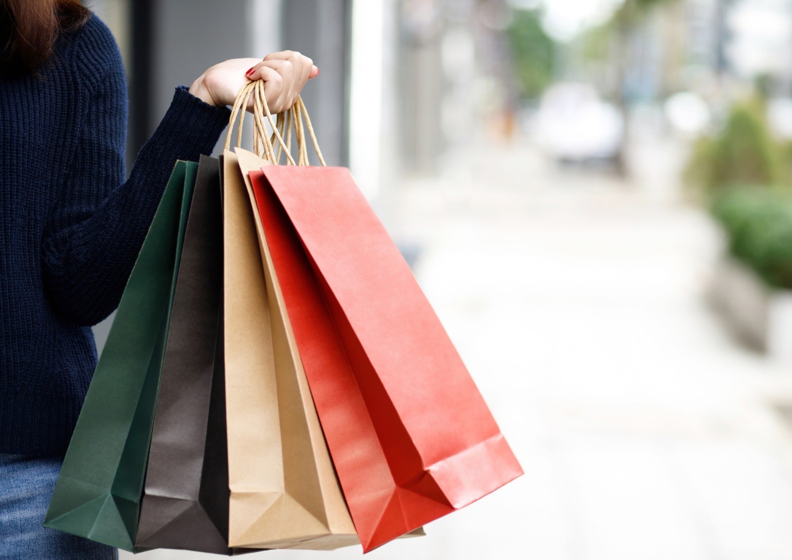 Persona sosteniendo varias bolsas de compras de diferentes colores