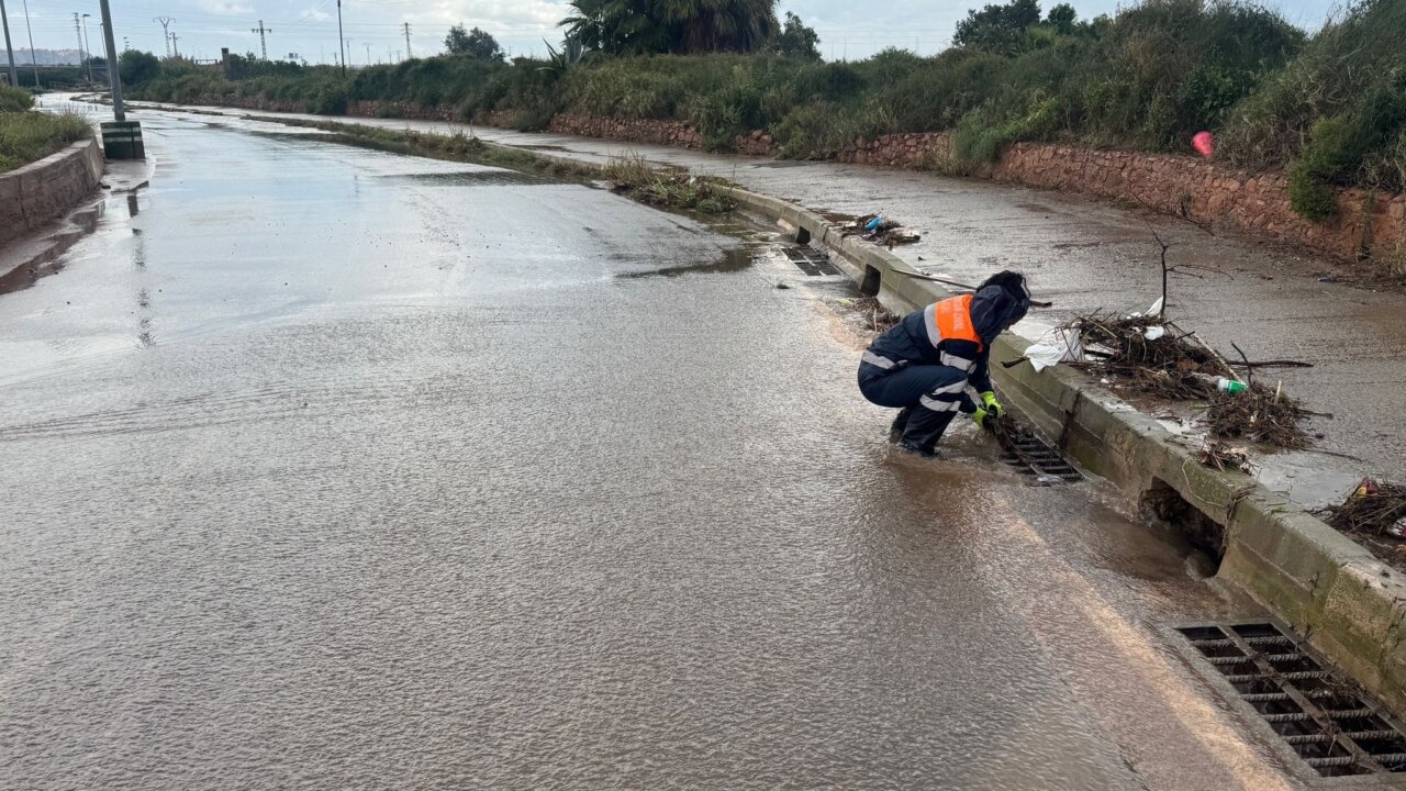Persona limpiando desagüe tras inundación en Valencia