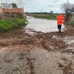 Persona con chaqueta naranja caminando por carretera afectada por inundaciones en Pucol