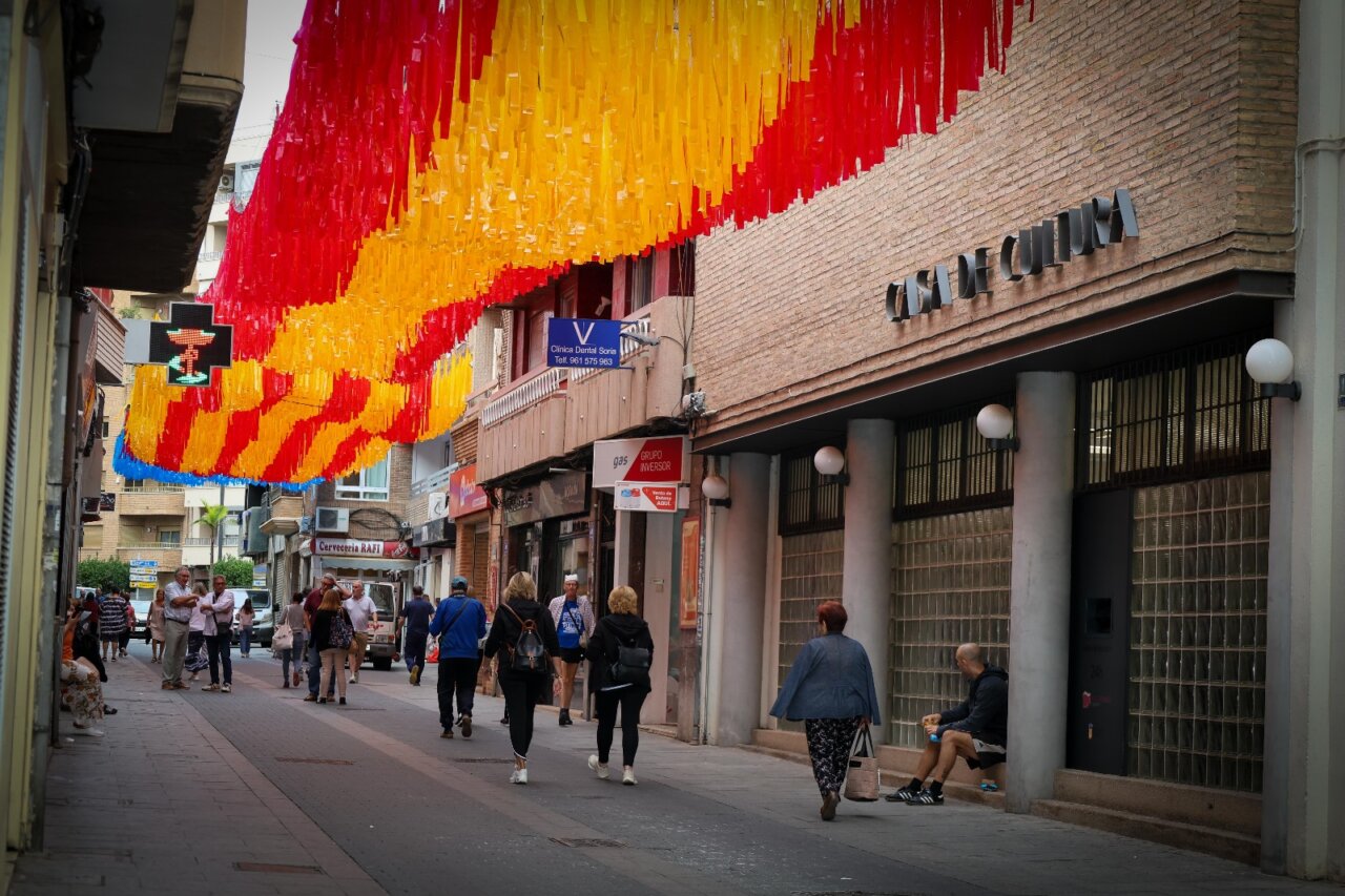 Calle Sagra decorada con lazos de colores de la Senyera y bandera de España