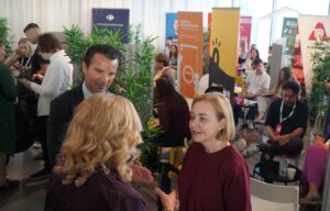 Personas conversando en una feria de empleo con stands coloridos.