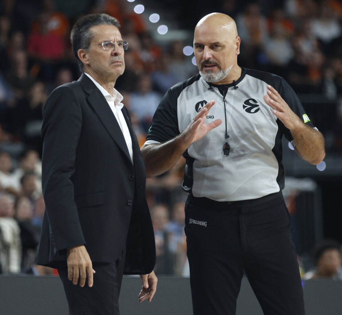 Entrenador y árbitro discutiendo durante un partido de baloncesto.