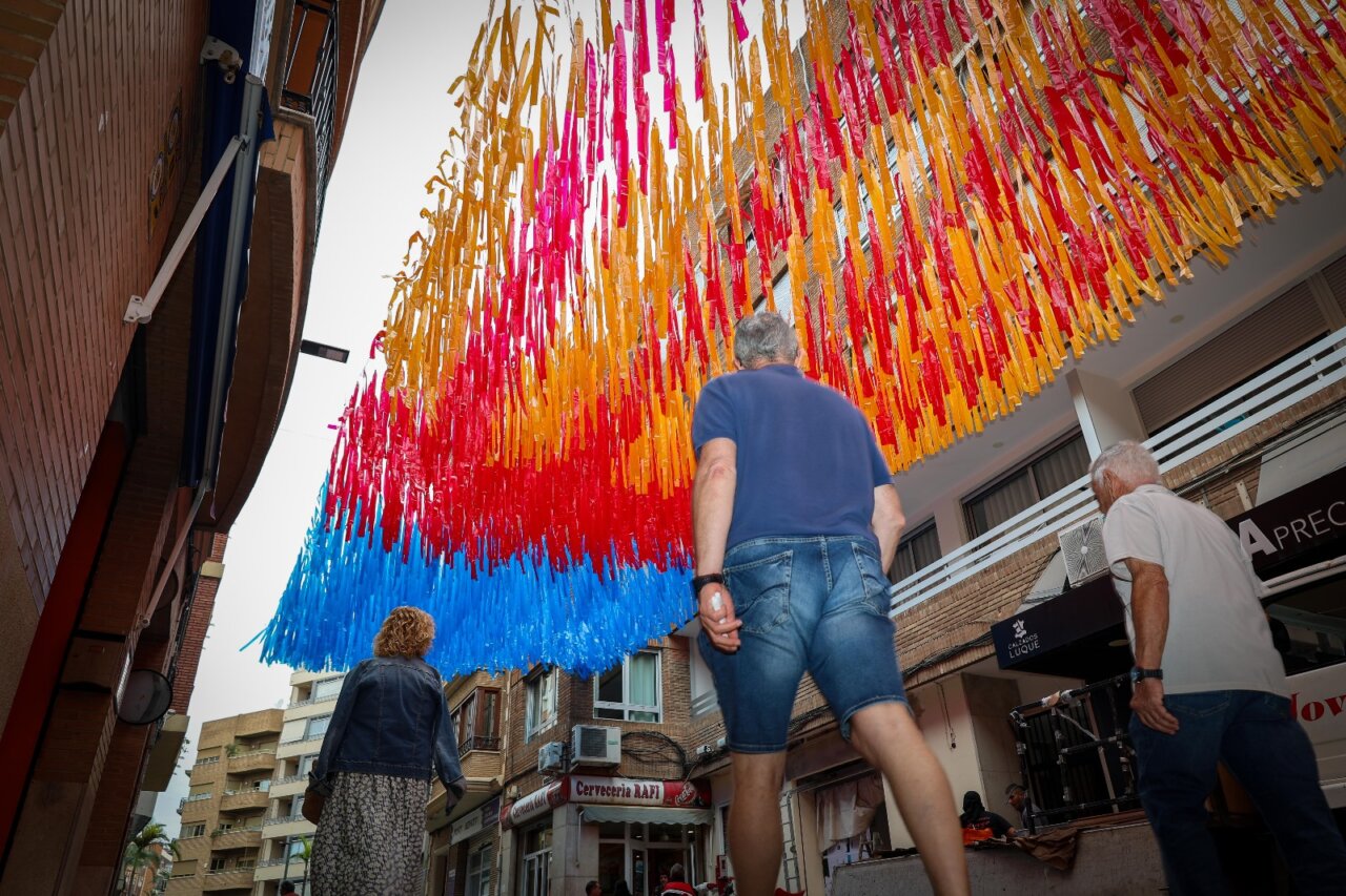 Decoraciones de la calle Sagra con lazos de colores rojo, amarillo y azul en Torrent.