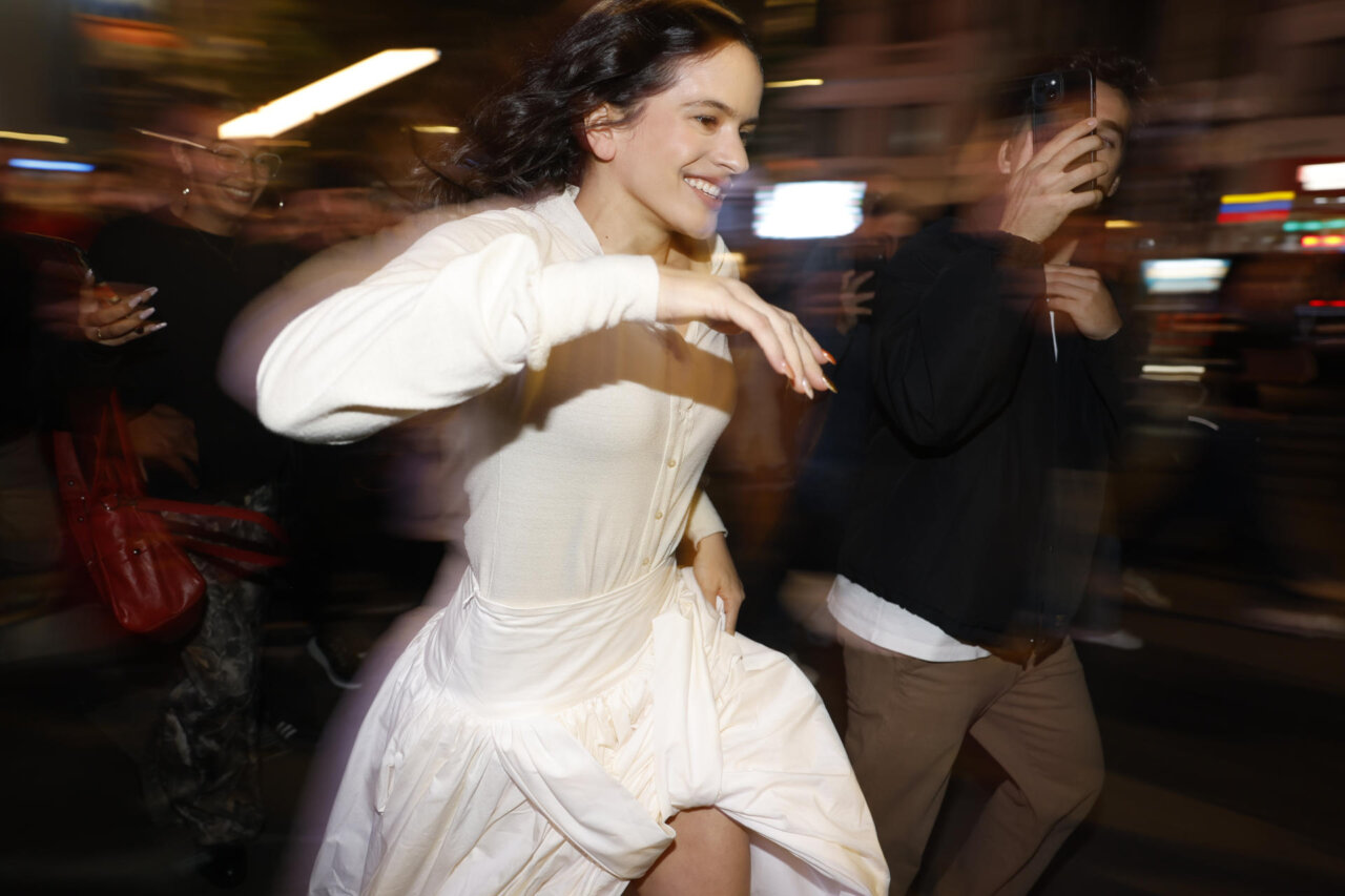 Rosalía corriendo en una calle iluminada por la noche.