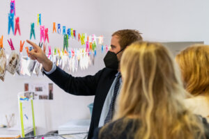Persona señalando fotografías colgadas en una exposición sobre restauración de imágenes