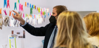 Persona señalando fotografías colgadas en una exposición sobre restauración de imágenes