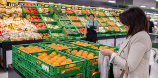 Mujer comprando caquis en la sección de frutas del Mercadona.