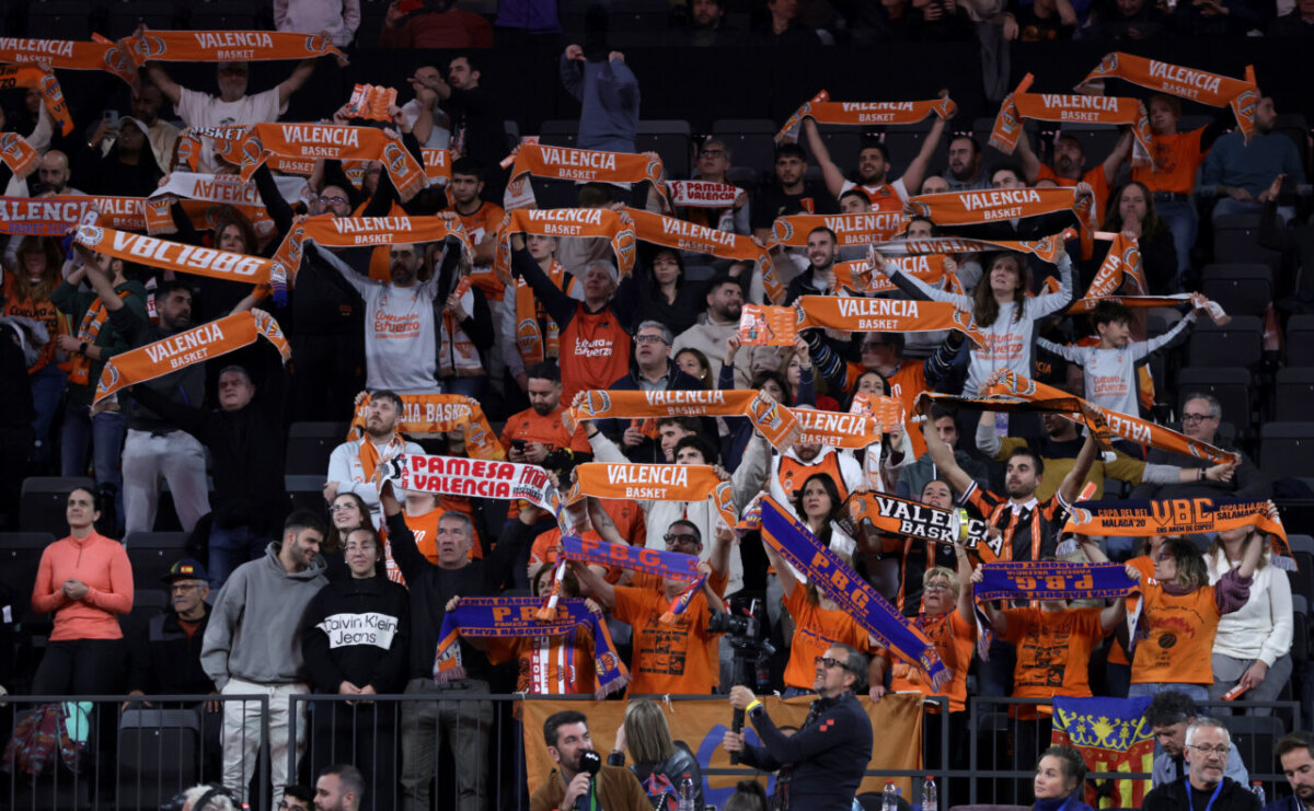 Aficionados del Valencia Basket animando en un partido con bufandas naranjas.
