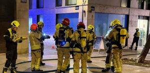 Bomberos trabajando en un incendio en Valencia, rescatando a una mujer.