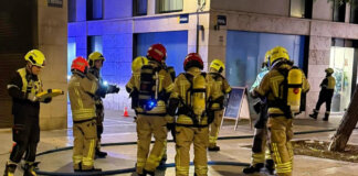 Bomberos trabajando en un incendio en Valencia, rescatando a una mujer.