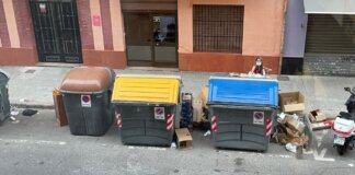 Contenedores de basura en una calle de València con residuos alrededor.