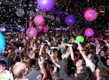 Multitud celebrando en una fiesta de Nochevieja con globos y confeti