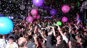Multitud celebrando en una fiesta de Nochevieja con globos y confeti