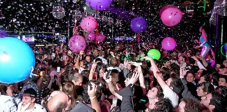 Multitud celebrando en una fiesta de Nochevieja con globos y confeti