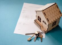 Modelo de casa de madera junto a llaves y documentos de hipoteca