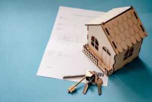 Modelo de casa de madera junto a llaves y documentos de hipoteca