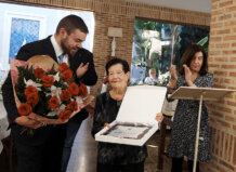 La Semana del Mayor 2025 de La Pobla de Farnals ofrecerá baile, teatro y una comida de homenaje Una mujer mayor recibiendo un reconocimiento en un evento social.