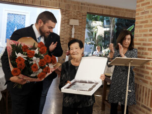 Una mujer mayor recibiendo un reconocimiento en un evento social.