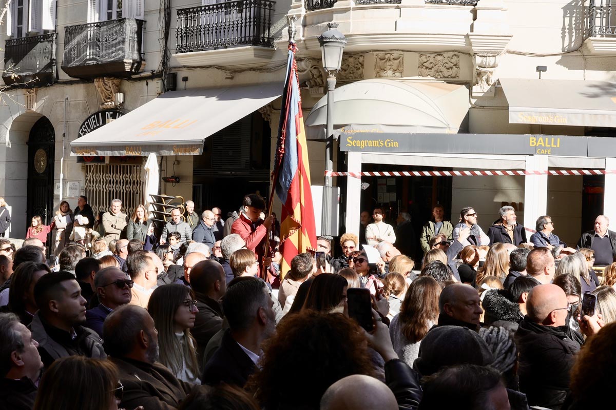 Ceremonia de homenaje con una multitud y una bandera en la plaza.