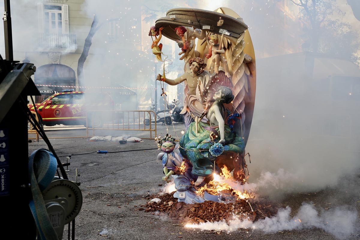 Escultura en llamas durante homenaje a Manolo Algarra con humo y fuegos artificiales.