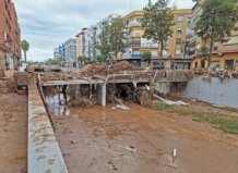 Vista de inundación en el Barranco de la Saleta con escombros y edificios cercanos.