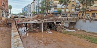 Vista de inundación en el Barranco de la Saleta con escombros y edificios cercanos.