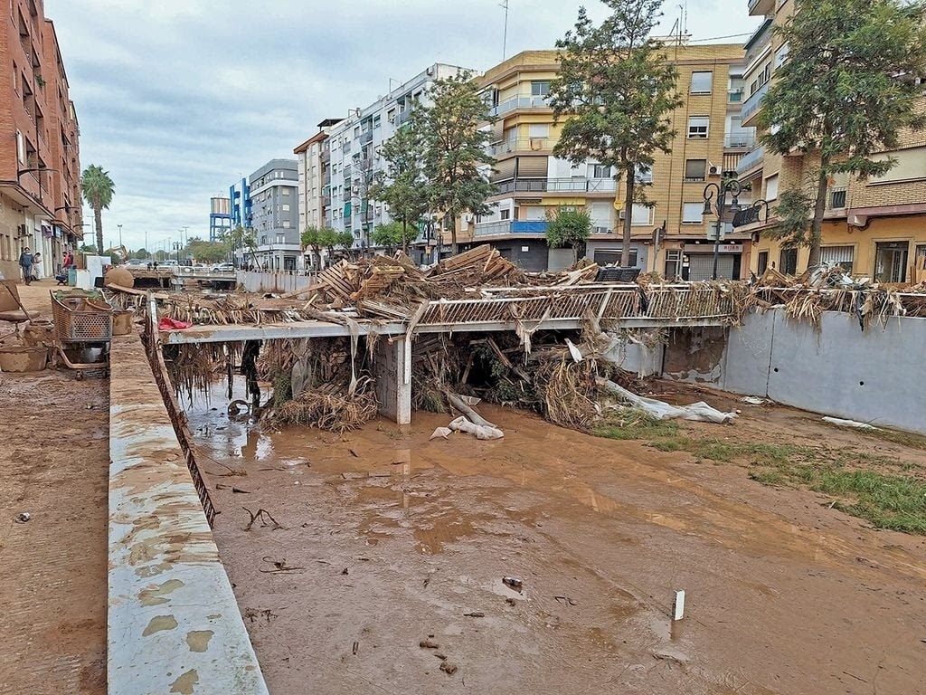 Vista de inundación en el Barranco de la Saleta con escombros y edificios cercanos.
