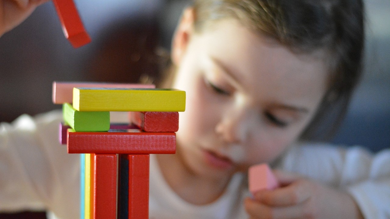 Niña jugando con bloques de madera de colores