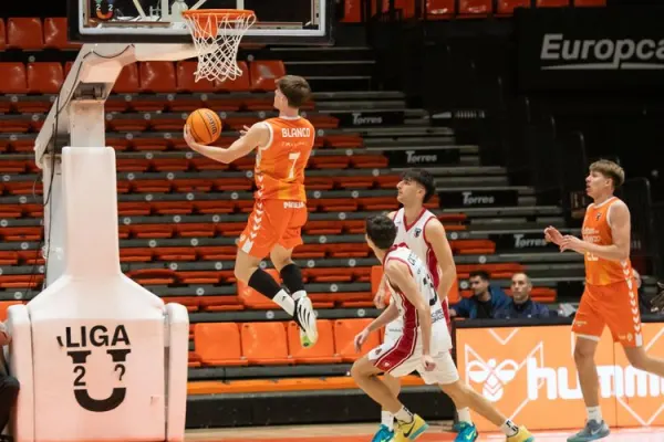 Jugador del Valencia Basket realizando un mate durante un partido emocionante.