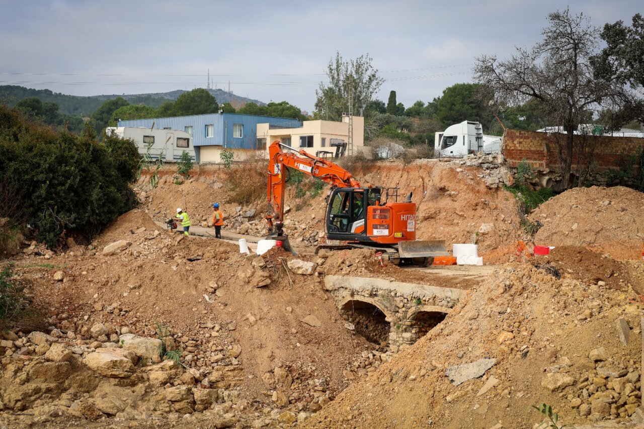 Obras de reconstrucción del Camí dels Arquets con maquinaria pesada y trabajadores