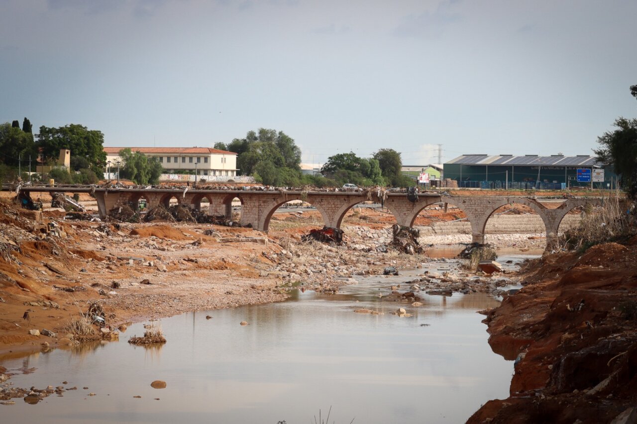 Puente dañado en Torrent tras inundaciones recientes con escombros alrededor.