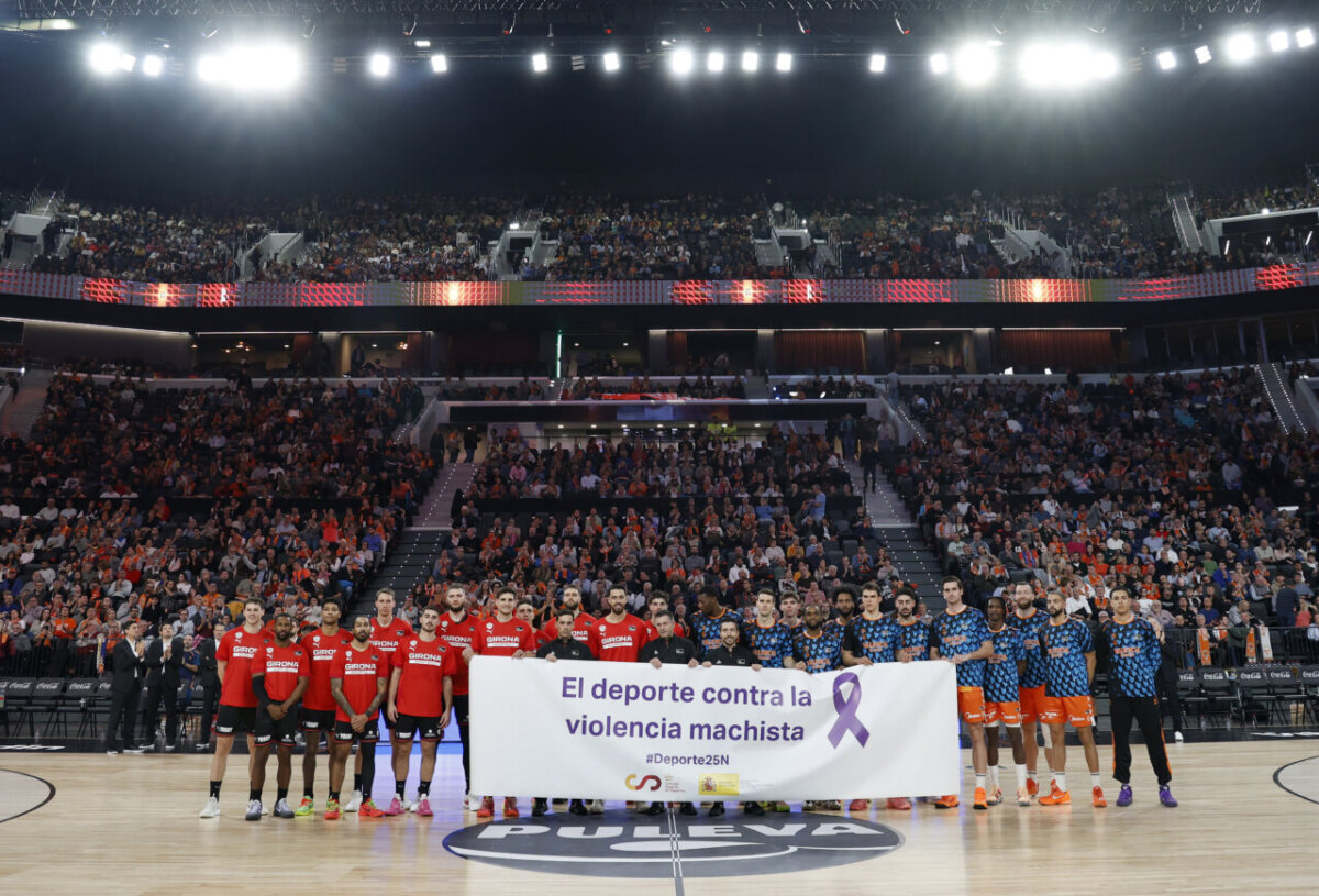 Jugadores de Valencia Basket y Girona mostrando un cartel contra la violencia machista.