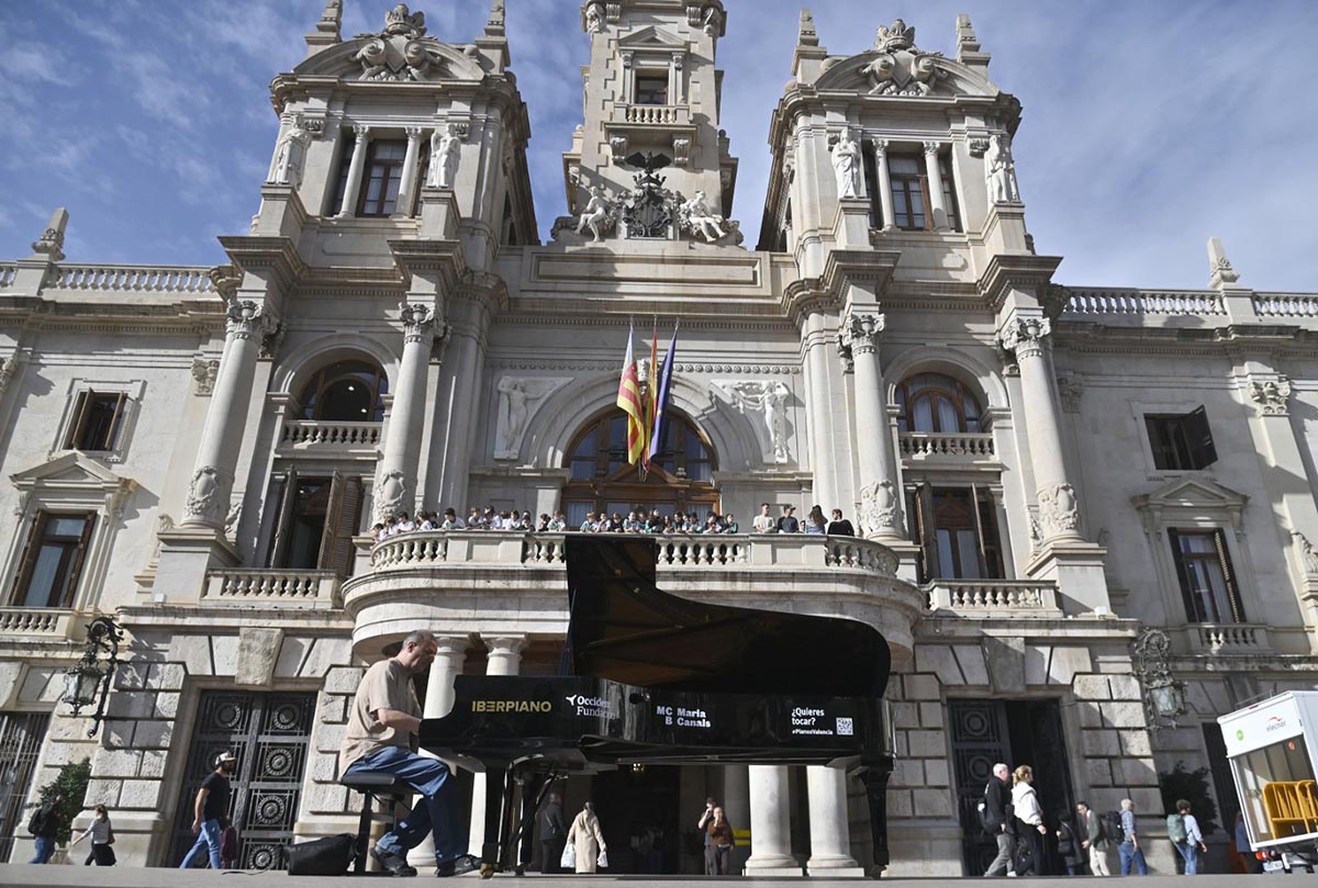Un hombre tocando un piano de cola en la plaza del Ayuntamiento de Valencia.